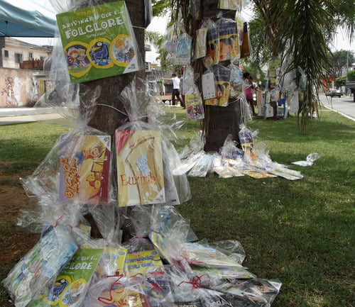 Foto da 7ª edição do festival, Clube da Comunidade Tide Setúbal, mostra parque com livros pendurados em troncos de árvores