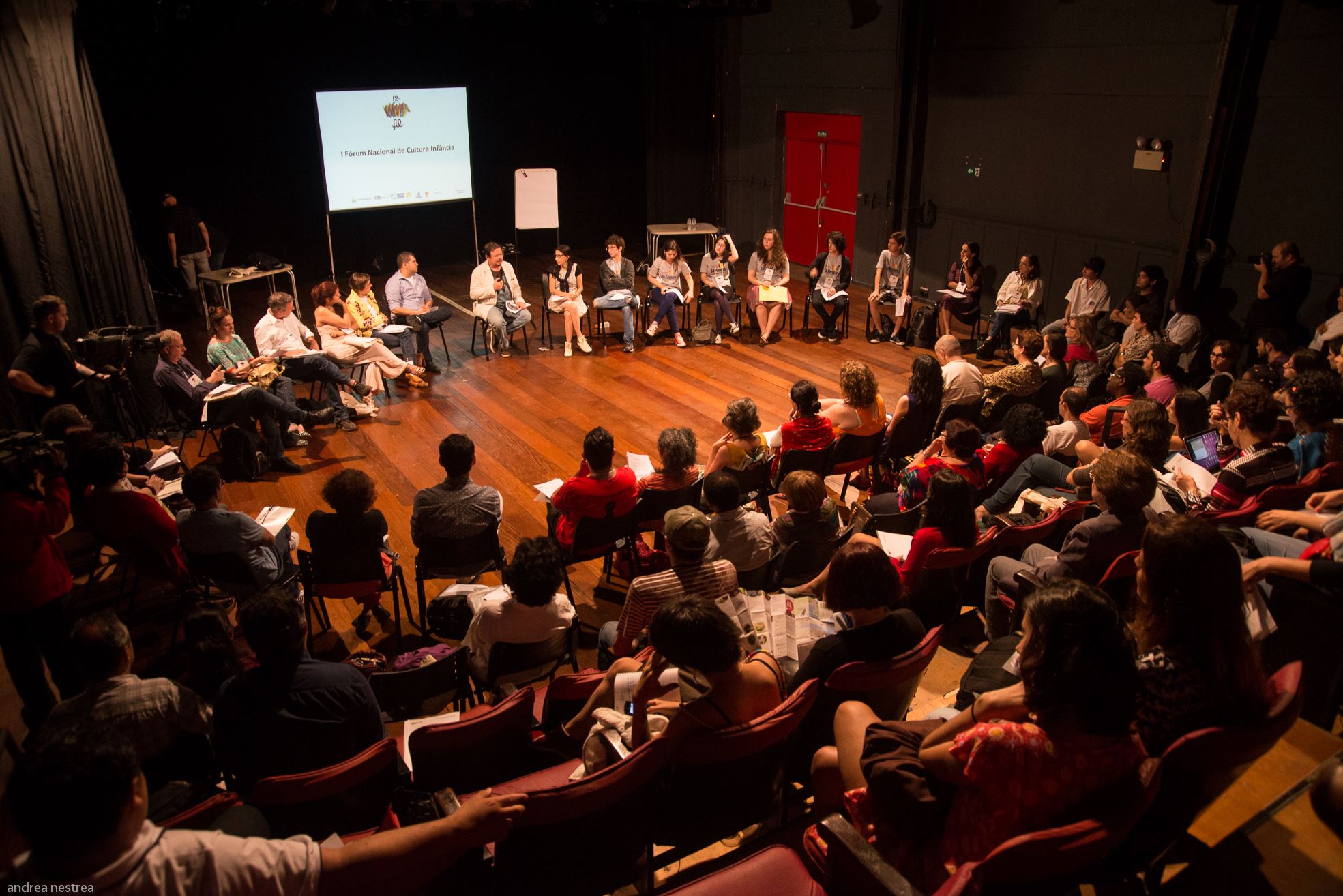 Roda de conversa com diversos participantes, em um galpão.