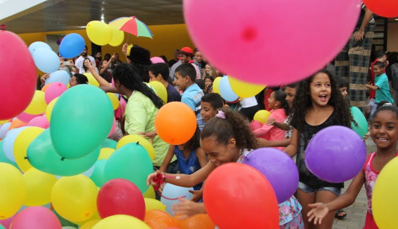 No novo Espaço Alana, pessoas se divertindo em um cenário repleto de bexigas coloridas.