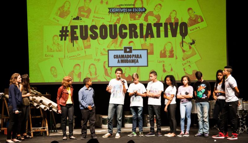 Foto mostra vencedores do Desafio Criativos da Escola apresentando o projeto. No fundo um telão escrito #eusoucriativo.