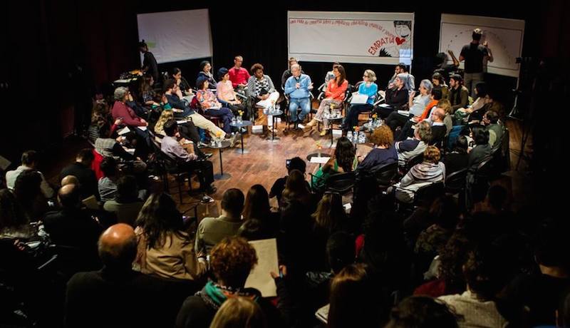 Participantes de evento em roda, debatendo ideias.