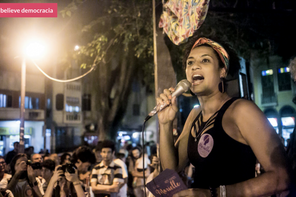 Foto de Marielle Franco falando em microfone