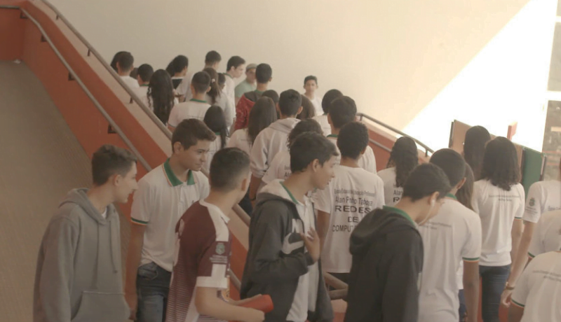 Jovens alunos caminham e sobem as escadas de uma escola.