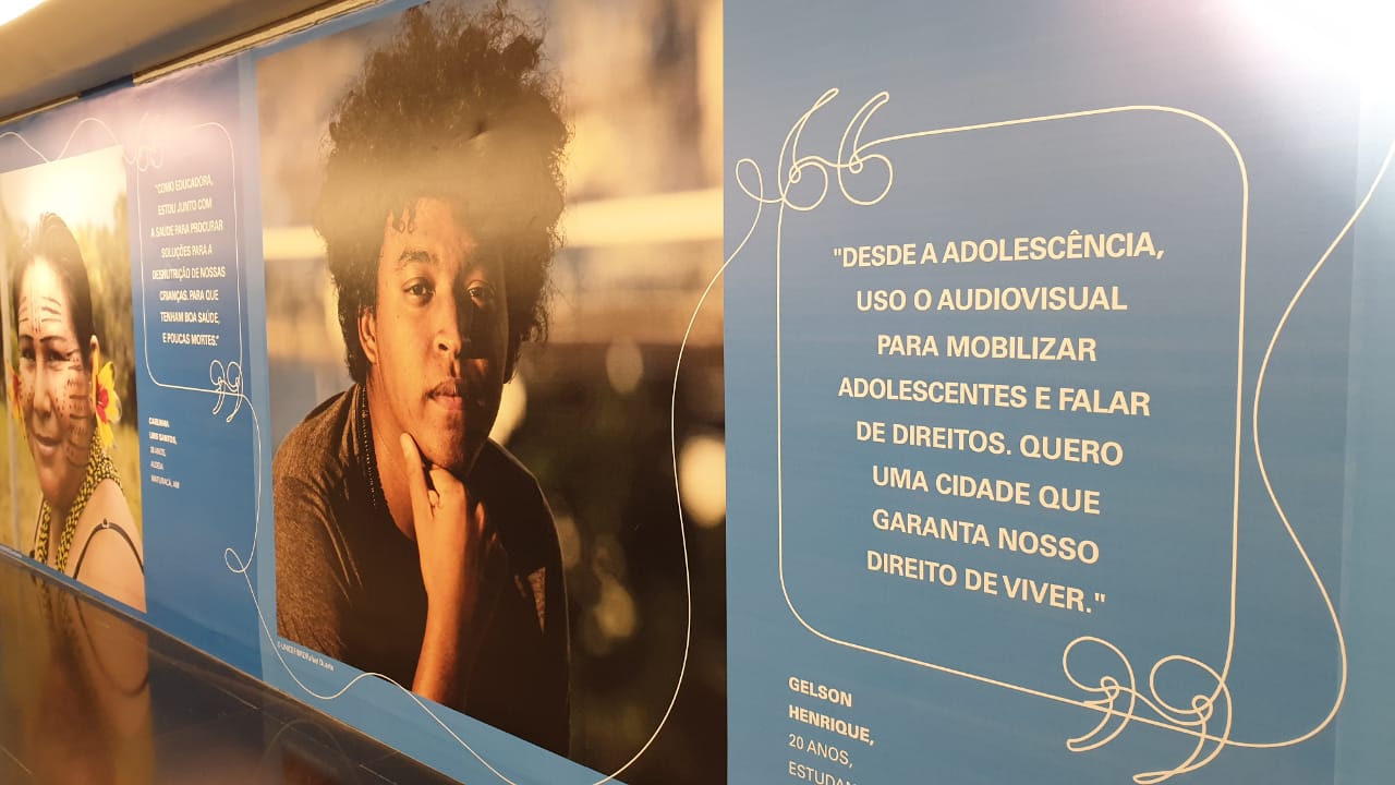 Corredor de exposição celebrando 30 anos da Convenção sobre os Direitos da Criança com foto de um jovem e uma frase