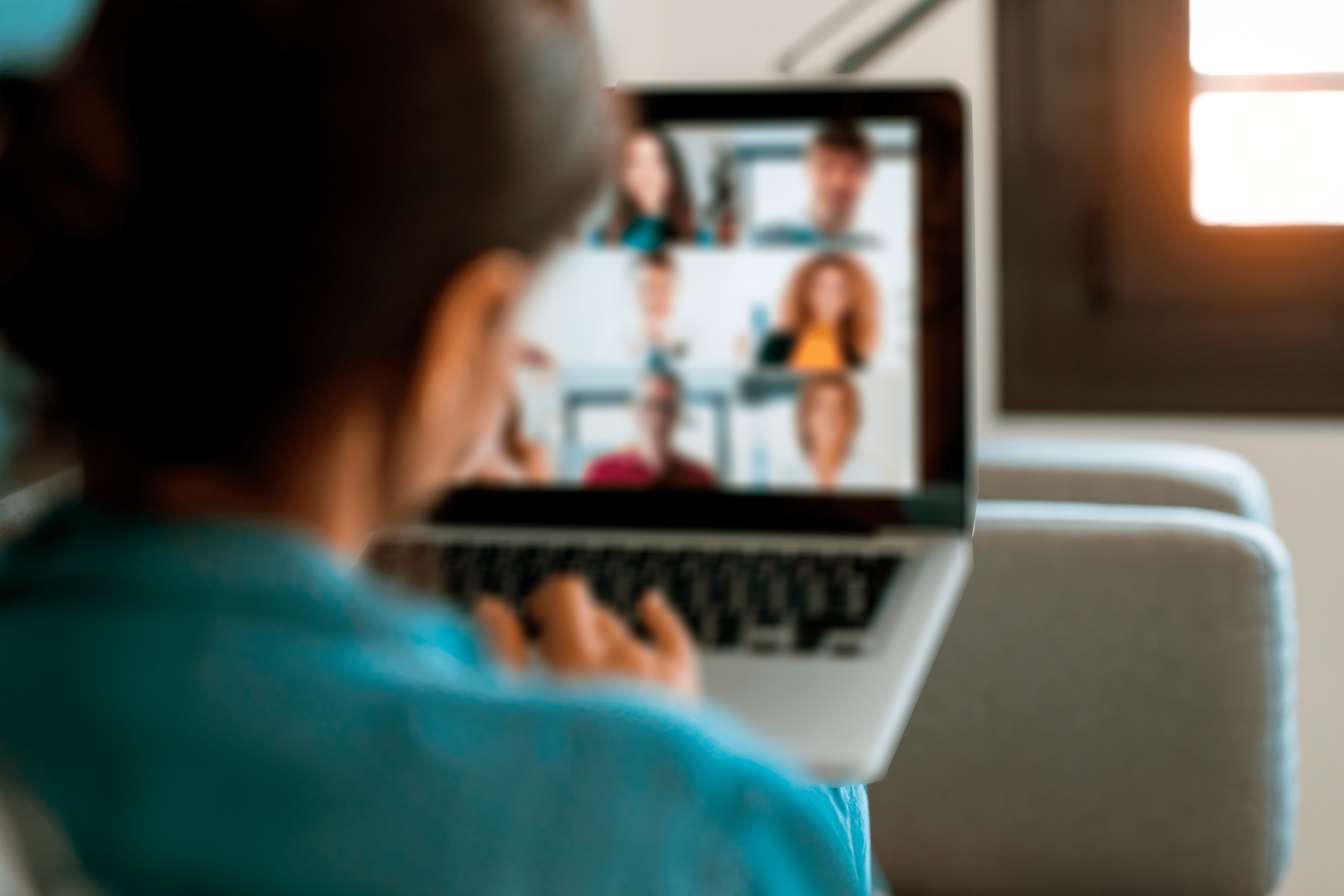 Foto de uma mulher de costas, na frente de um computador, participando de uma audiência por videoconferência no Sistema de Justiça Juvenil