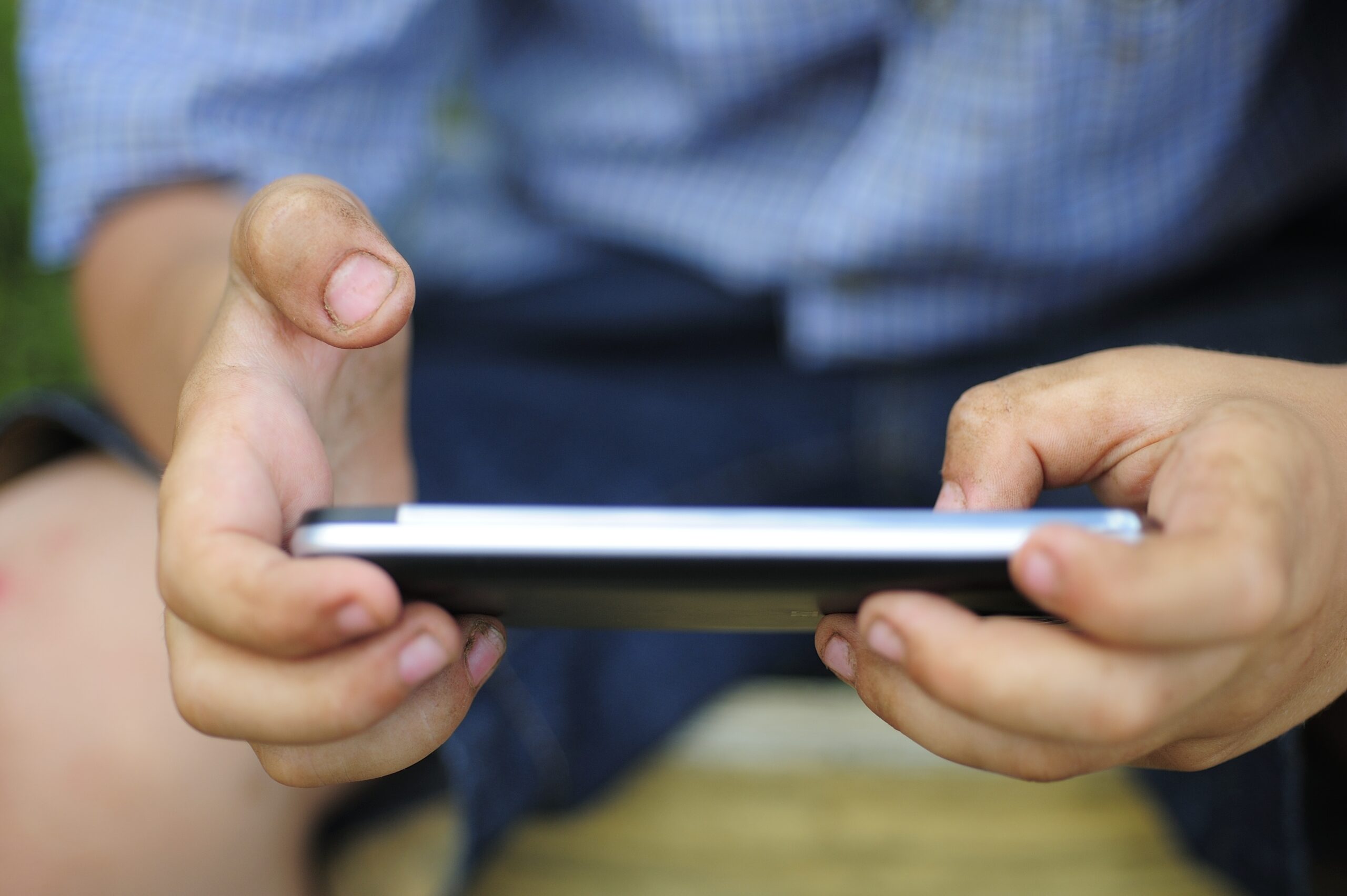 Foto das mãos de uma criança usando um celular faz referência à importância de se garantir os direitos das crianças no ambiente digital