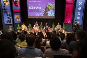 Nilma Lino Gomes, Márcia Lima, Lucimar Dias e Barbara Carine estão sentadas em um palco, debatendo de frente para uma plateia